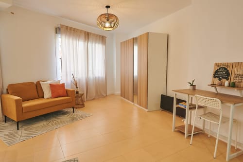 Modern apartment living room with orange sofa, wooden wardrobe, desk, and city views at Mediterranea Sunny Keys, Castelló