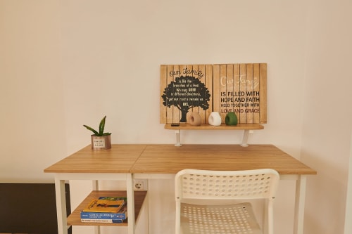 Modern apartment desk workspace with wooden furniture, white chair, succulent plant, and inspirational wall art in Castelló