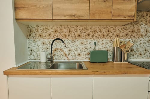 Modern kitchen with wooden cabinets, stainless steel sink, and botanical backsplash in Mendez Nuñez Sunny Flat, Castelló