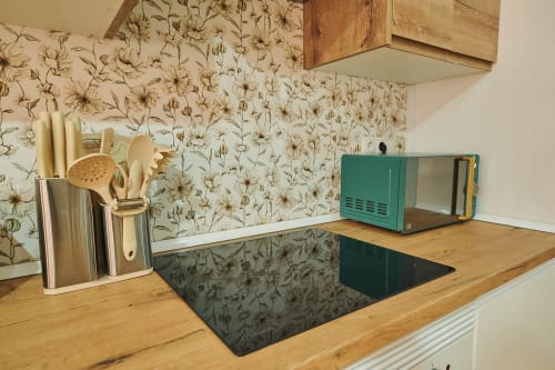 Kitchen counter with cooking utensils, teal microwave, and dried flower wallpaper in Mendez Nuñez apartment