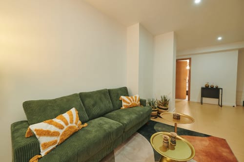 Modern living room with green corduroy sofa and orange pillows at Mendez Nuñez Sunny Flat in Castelló de la Plana