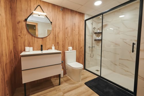 Modern bathroom with wooden walls, white vanity, toilet, and walk-in shower at Mediterranea Sunny Keys apartment in Castelló