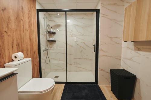 Modern bathroom with marble shower enclosure, black frame glass doors, and wooden accents at Mediterranea Sunny Keys