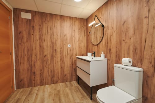 Modern bathroom with wooden walls, white sink vanity, toilet, and shower fixture at Mediterranea Sunny Keys apartment in
