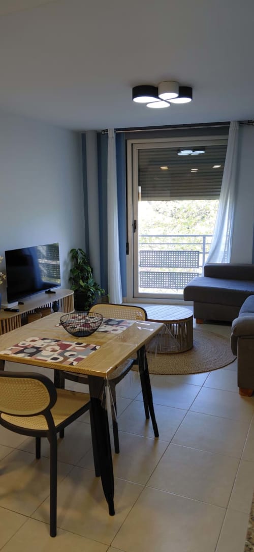 Salon moderne au Sunny Flat Pont de Ferro à Benicàssim, avec table de salle à manger, TV, canapé et balcon avec vue sur la ville