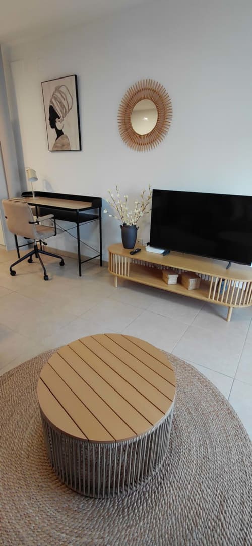 Salon moderne d'appartement avec bureau, meuble TV, table basse ronde et miroir décoratif à Méditerranée Sunny Keys