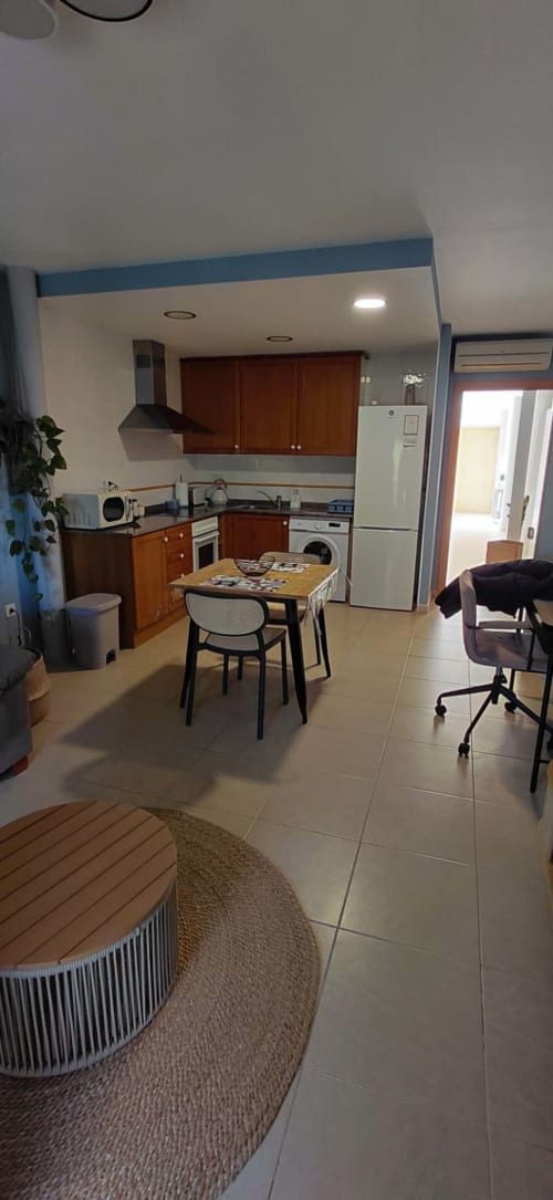 Cuisine moderne et coin repas de l'appartement Sunny Flat à Pont de Ferro, Benicàssim, avec armoires en bois, électroménagers blancs