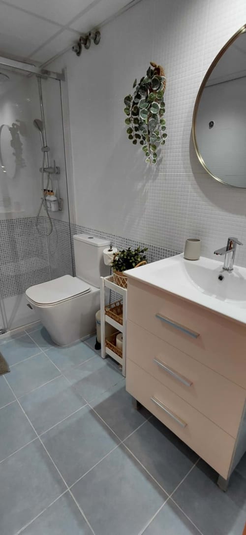 Salle de bain moderne du Pont de Ferro Sunny Flat à Benicàssim, avec sanitaires blancs, meuble vasque, toilettes, miroir rond et éléments de décoration