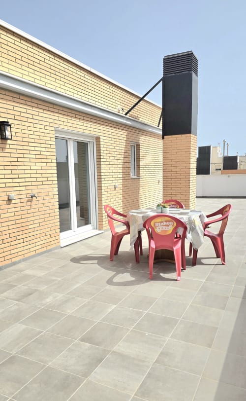 Sunny rooftop terrace with red chairs and table at García Sanguesa Sunny Flat in Benicàssim, Spain