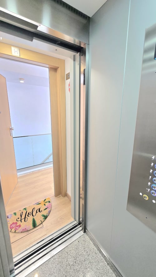 Modern elevator interior at Mediterranea Sunny Keys apartment in Benicàssim with 'Olfola' welcome mat and stainless steel