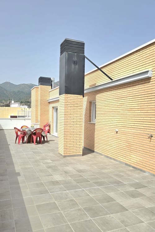 Sunny rooftop terrace at Mediterranea Sunny Keys, Benicàssim apartment with red chairs and mountain views