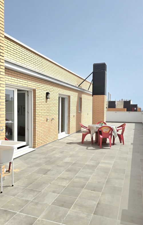 Sunny rooftop terrace with red chairs and table at Mediterranea Sunny Keys apartment in Benicàssim