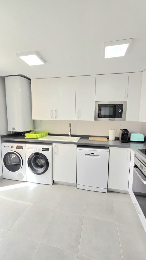 Modern kitchen with white appliances, washer/dryer, and dishwasher in García Sanguesa Sunny Flat apartment