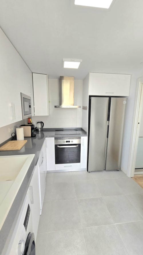 Modern kitchen in García Sanguesa Sunny Flat, Benicàssim apartment with white cabinets, stainless steel appliances, and gray