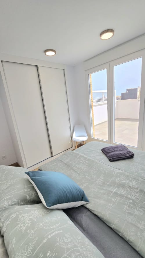 Modern bedroom at García Sanguesa Sunny Flat in Benicàssim with bed, blue pillow, sliding wardrobe, glass doors to terrace