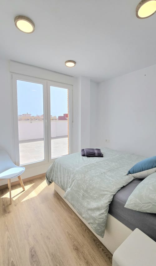 Modern bedroom with bed, recessed lighting, terrace doors overlooking Benicàssim cityscape at García Sanguesa Sunny Flat