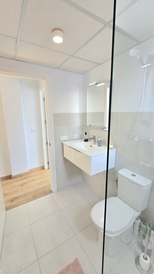 Modern bathroom at García Sanguesa Sunny Flat with walk-in shower, white vanity, toilet, and beige tile flooring