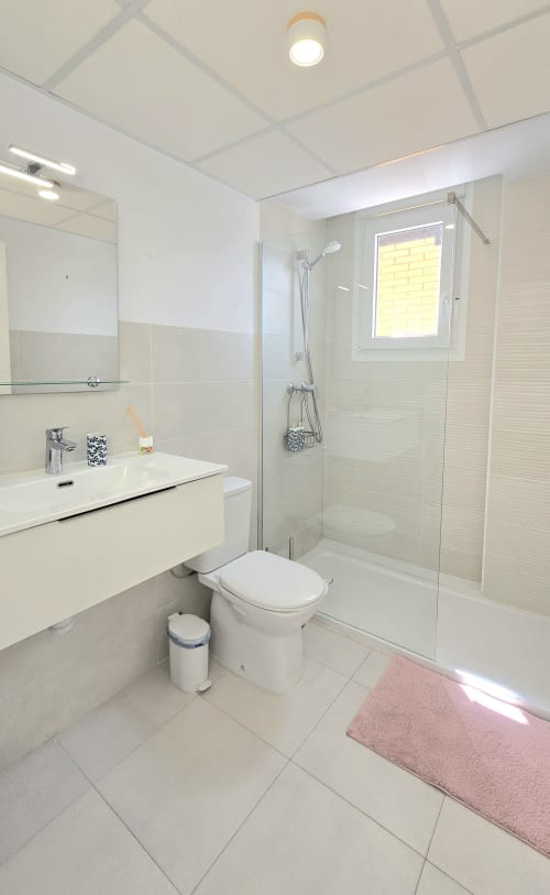 Modern bathroom at Mediterranea Sunny Keys with white vanity, glass shower enclosure, and pink bath mat