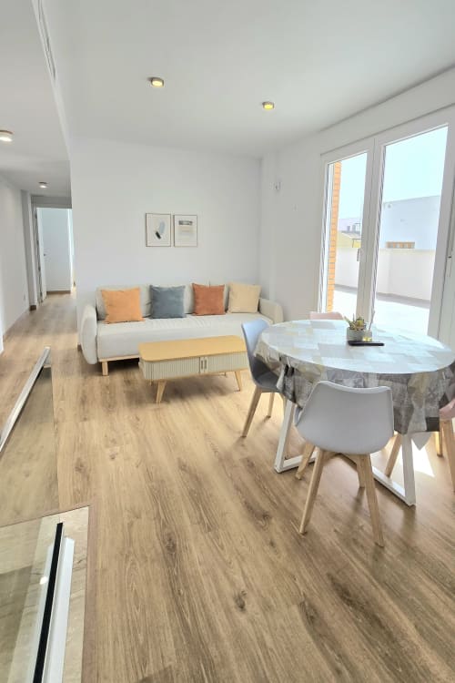 Modern living room in García Sanguesa Sunny Flat, Benicàssim, with sofa, dining table, and terrace access