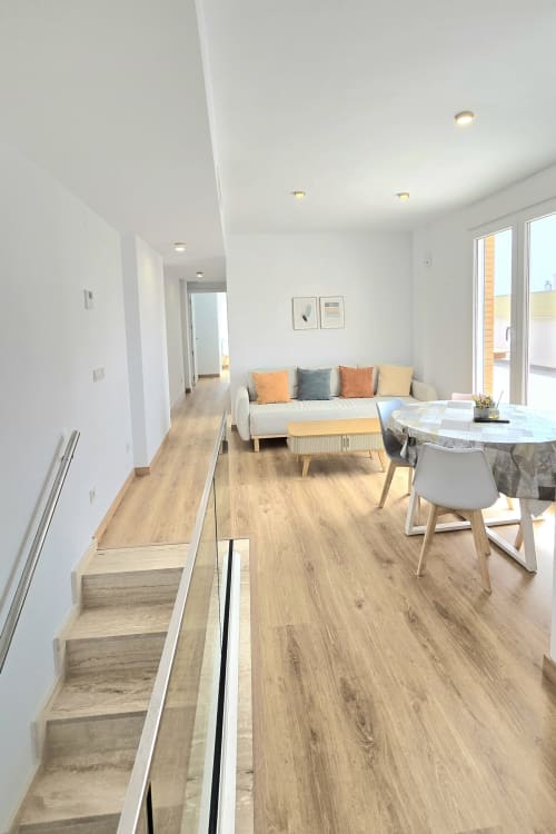 Modern apartment living area with wooden floors, beige sofa, dining table, and glass doors at García Sanguesa Sunny Flat in