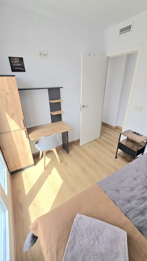 Modern apartment workspace at Mediterranea Sunny Keys in Benicàssim with wooden desk, white chair, and sunlit flooring