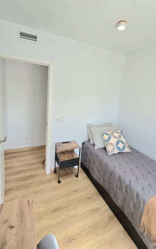Bright bedroom at Mediterranea Sunny Keys with gray bed, wooden nightstand, and modern amenities in Benicàssim apartment