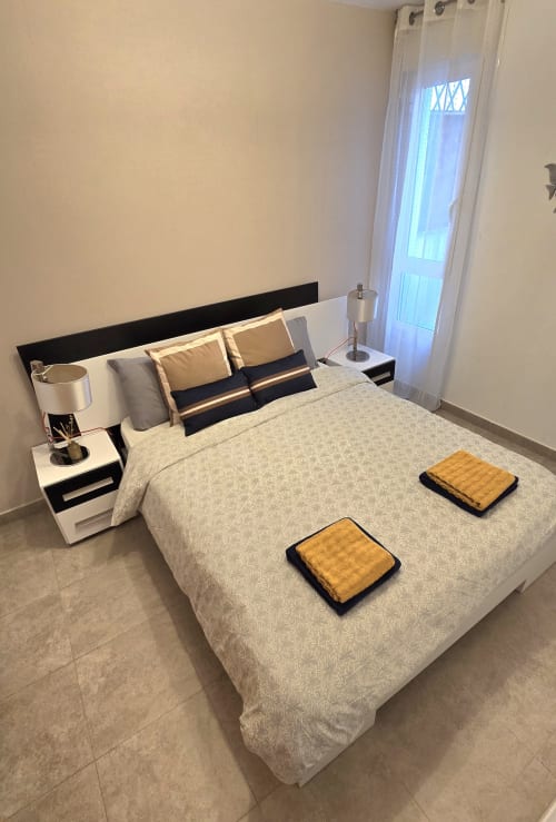 Modern bedroom at Mediterranea Sunny Keys apartment in Benicàssim with beige bedding, black headboard, and city view