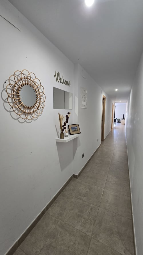 Modern hallway entrance of Els Dolors Sunny Flat in Benicàssim with decorative mirror and welcome sign