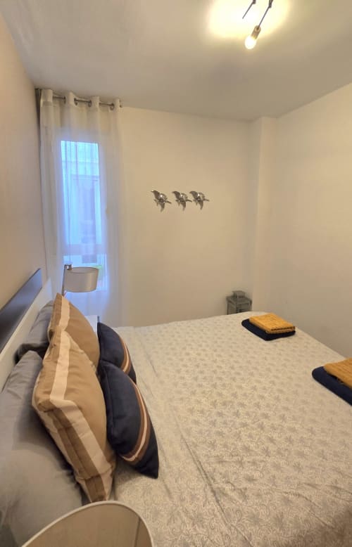 Bright bedroom at Mediterranea Sunny Keys apartment in Benicàssim with bed, pillows, window with sheer curtains, bird wall