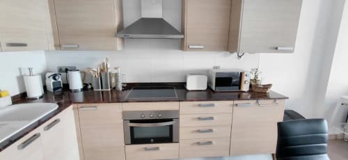 Modern kitchen in Els Dolors Sunny Flat apartment, Benicàssim, with light wood cabinets, dark countertops, and stainless