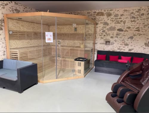 Espace détente spa à la Filante B&B avec sauna en bois, fauteuil massant et murs en pierre à Saint-Christophe-du-Bois