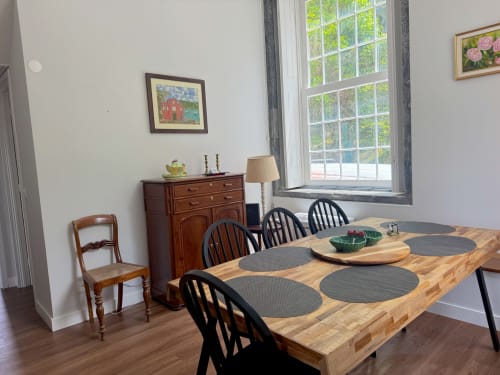 Dining area in Casa Dos Barcos cottage, Furnas, with wooden table, black chairs, and lake views through large windows