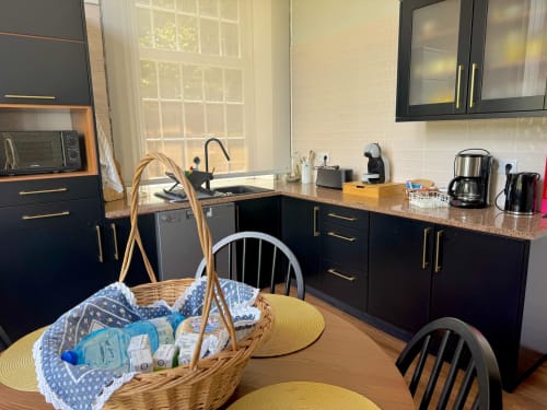 Modern kitchen with black cabinetry, granite countertops, and dining area in Casa Dos Barcos cottage, Furnas São Miguel