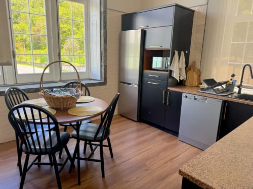 Modern kitchen and dining area at Casa Dos Barcos Furnas cottage with black cabinetry, stainless steel appliances, wooden