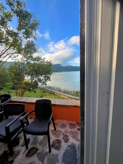 Lakeside cottage patio at Casa Dos Barcos Furnas with seating overlooking calm lake waters and mountains