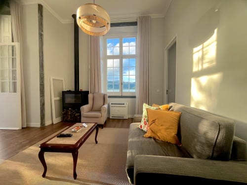 Bright living room with lake view at Casa Dos Barcos Furnas cottage, featuring sofa, armchair, fireplace, and natural light