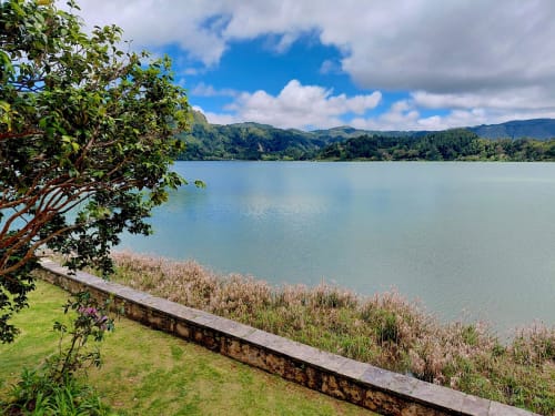 Serene lake view from Casa Dos Barcos cottage in Furnas, São Miguel with lush mountains and green grounds