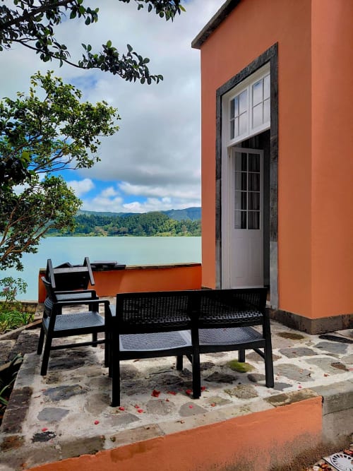 Black chairs on stone patio at Casa Dos Barcos Furnas cottage in Azores with turquoise lake and mountains