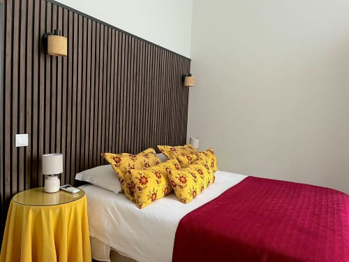 Bedroom at Casa Dos Barcos in Furnas with yellow patterned pillows, red blanket, and modern black wood headboard