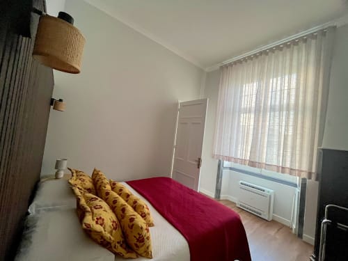 Bright bedroom at Casa Dos Barcos cottage in Furnas with red bedcover, yellow patterned pillows, white door, and lake-view