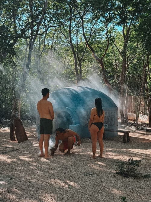 Familia refrescándose en la ducha natural de cenote en Hotel Boutique Cenote Secreto Maya, Valladolid, Yucatán
