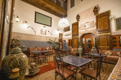 Cour du Riad Dar Tahri à Fès avec zellige ouvragé, lanternes en laiton, arcades et mobilier marocain traditionnel