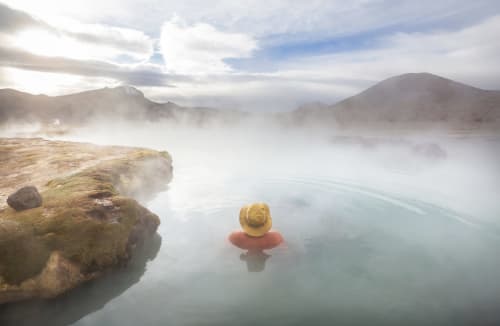 Un client se détend dans une source thermale géothermale entourée de vapeur et de montagnes près de Fès