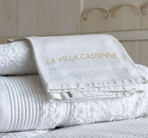 Luxury white towels branded with La Villa Cassinne embroidery, displayed at the Cotentin bed and breakfast in Montebourg