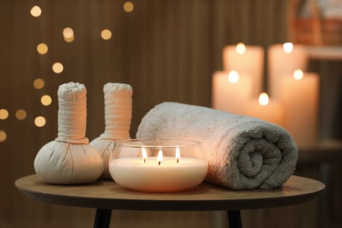 Ambiance spa relaxante au Riad Dar Tahri Fès avec bougies, serviettes et sachets de plantes sur table en bois