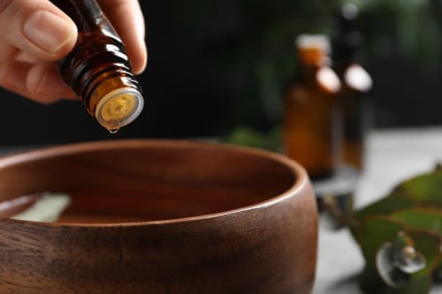Un compte-gouttes d'huile essentielle versé dans un bol en bois au spa bien-être du Riad Dar Tahri à Fès, Maroc