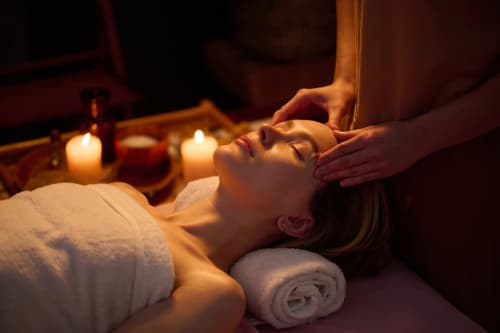 Femme recevant un massage relaxant de la tête à la lumière des bougies au spa Riad Dar Tahri à Fès