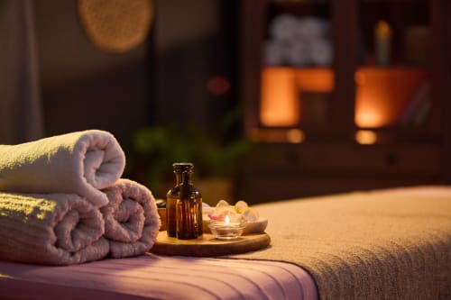 Ambiance spa au Riad Dar Tahri de Fès avec serviettes roulées, huiles essentielles et bougies sur lit de massage