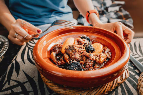 Femme servant un tajine traditionnel au Riad Dar Tahri à Fès, Maroc