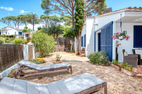 Terrassa de jardí privat amb tumbones a Casa Golfet, Palafrugell, vila blanca amb persianes blaves